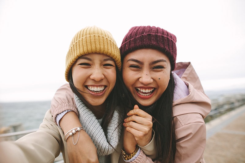 Two friends happily take a selfie together after visiting the dentist.